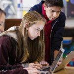 học sinh trung học làm bài luận trên laptop